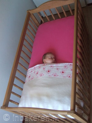 Baby in kort opgemaakt bed